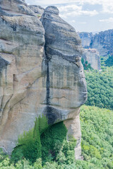 Rugged cliff with layered textures and sparse greenery clinging to the rock face in Meteora, Greece