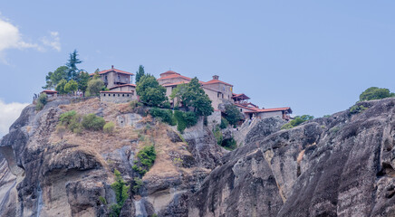Ancient monasteries perched atop towering cliffs surrounded by lush trees in Meteora, Greece