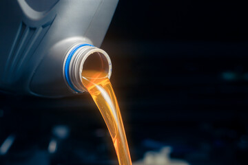 Pour engine oil from the lubricant bottle. Engine background, oil change shop engine service...