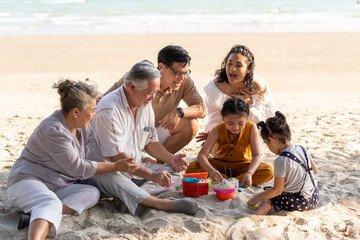Fototapeta premium Happy multi-generation Asian family enjoy summer outdoor lifestyle activity vacation together. Smiling grandparents, father and mother with two child girl kid having fun playing together on sand beach