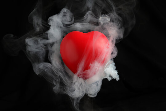 Red love hart flowing flying though white fog smoke mist on black background