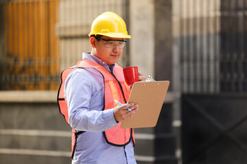 Fototapeta premium mexican man worker with hard hat and goggles looking at logbook holding coffee cup