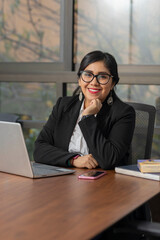 Portrait of a Mexican businesswoman in her office looking at the camera smiling.
