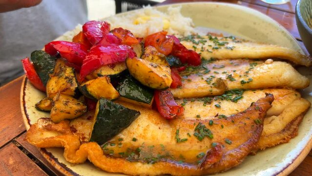 Tasty fried fish with vegetables and white rice on a plate, traditional Spanish food in Spain, 4K shot