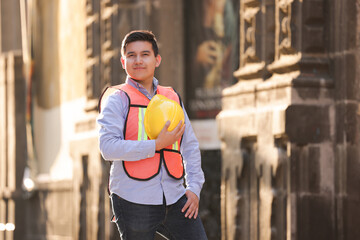mexican working man engineer smiling, looking at the camera holding helmet in proud posture 