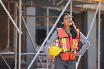 mexican woman engineer worker smiling and looking at the horizon with construction background