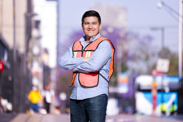 mexican working man smiling looking at the camera with his arms crossed and city background
