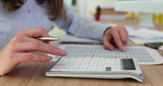 Woman calculates expenses using calculator at workplace