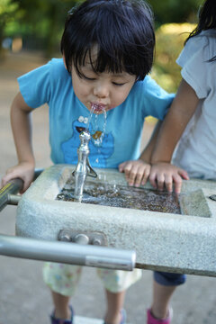 公園の水飲み場で水を飲む子供たち / Children drinking water at a water fountain in a park