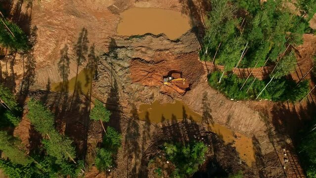Drone shot of an excavator in the forest creating logging roads.