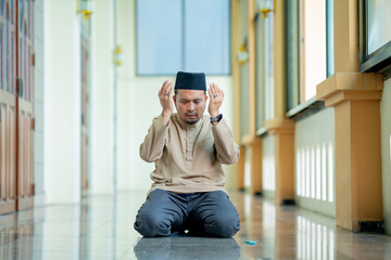 Fototapeta premium Ramadan, Muslim, Isalam, An Asian Muslim man is praying with peace in the beautiful mosque, giving a powerful atmosphere of faith, with copy space, Islam concept.