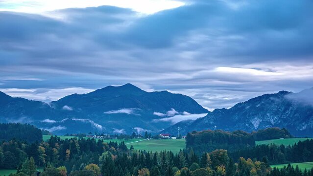 Time lapse of Austrian alps Landscape European mountain range green blue skyline Valley, clouds in motion becoming dusk, green agricultural fields