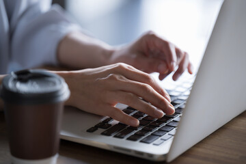 Closeup of a woman's hand typing on a computer for business at an office or cafe No face	