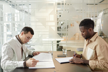 Side view portrait of two male entrepreneurs writing notes at opposite sides of table, copy space - 779396342