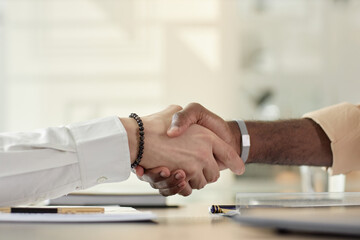 Side view closeup of two male hands in handshake over meeting table, copy space - 779396796