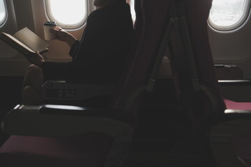Blonde female tourist checking incoming notification on smartphone sitting on seat of airplane with...