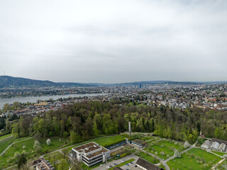 Aerial view over Swiss City of Zürich with woodland and Lake Zürich wiht local mountain Uetliberg in the background on a cloudy spring day. Photo taken April 7th, 2024, Zurich, Switzerland.