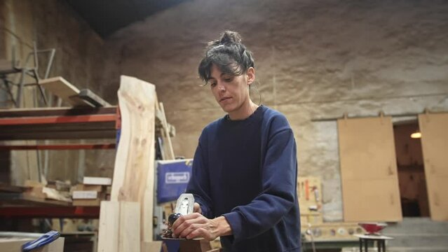 Woman carpenter planing wood block. Feminist girl process timber bar. Male carpentry work. Female joiner made woodwork. Feminism worker. Person create art project. Diy master class workshop. Hand job.