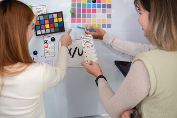 A team of software developers brainstormed to design a smartphone application by planning on a whiteboard and using it to develop the application system.