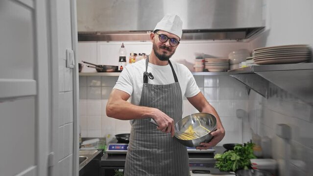 Male head chef prepare tasty fresh dish. Man cook meal restaurant kitchen. Young adult person work at cafe cuisine wear white hat. Guy make diet lunch food. Culinary worker job. Cookery staff uniform.