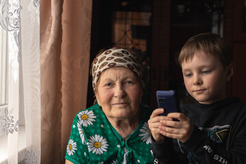 Boy using his smartphone near his grandma