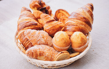 Sweet bakery products and croissant in the basket captured from above (top view), white background