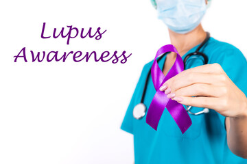Female doctor in blue uniform with purple awareness of ribbon in hand for Lupus Awareness