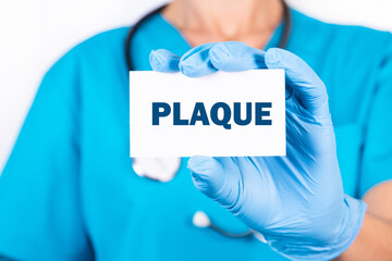 A doctor in blue medical uniform holds a card with the name of the diagnosis, the word PLAQUE....