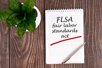 Fair Labor Standarts Act FLSA - handwriting on a notebook with pen