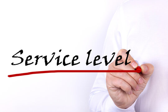 A person writes text, a word, the phrase Service Level with marker on a light background. Business concept.