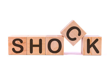 Word SHOCK is made of wooden building blocks lying on the table and on a light background. Concept.