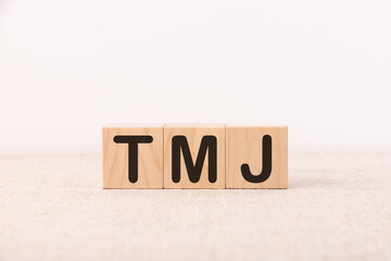 TMJ - acronym from wooden blocks with letters, abbreviation TMJ temporomandibular joint syndrome,...