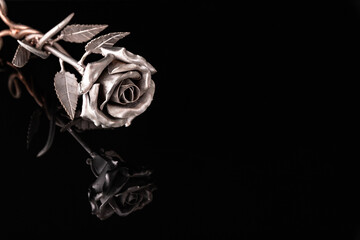 Iron rose made of metal lying on a black background. Symbol of sorrow, courage, steadfastness,...