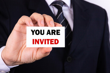 Obraz premium Businessman shows a sign with the text YOU ARE INVITED. Business concept