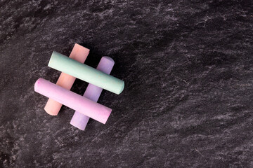 Close-up of a blackboard with pieces of colored chalk laid out in the form of a hashtag.