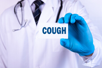 A doctor in medical clothing puts a card with the text COUGH. Medical concept.