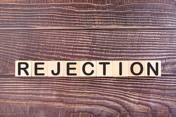The word REJECTION, written with wooden cubes on a wooden background.