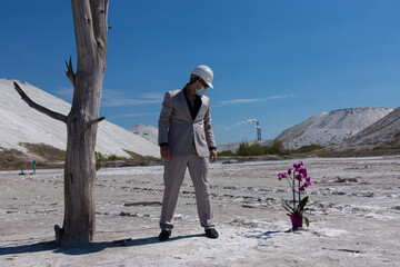 An engineer in a white helmet against the background of the industrial zone protects an orchid...