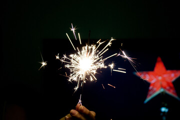 Burning sparkler in hand on dark background. New Year's Eve