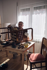 Man working in a small home workshop for furniture repairing and restoration.