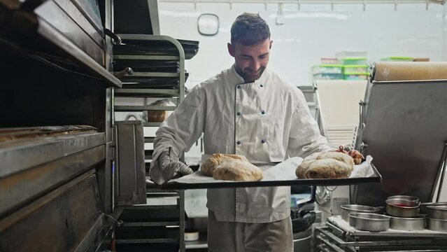Happy male baker take bread out of hot oven. Smile man cook tasty fresh loaf. Cafe staff bake warm eat bun. Bakery guy look at camera. 40s head chef portrait. Person making meal job. Pastry food house