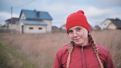 Portrait of a teenage girl in glasses wearing red clothes outside in the fall.