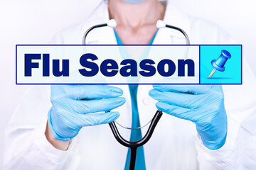 FLU SEASON text is written on the background of a doctor holding a stethoscope. Medical concept.