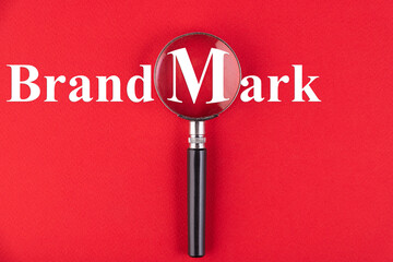 The word Brand Mark through a magnifying glass on a red background.