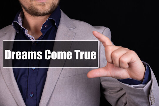 A businessman holding a business icon with the text Dreams come true written on it.