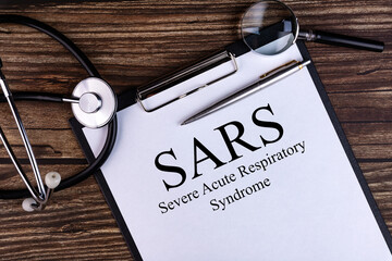SARS text is written on a tablet lying on a dark table with a stethoscope and a magnifying glass....