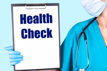 HEALTH CHECK text is written in a notebook, which the doctor holds and shows in his hands. Medical...