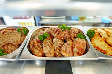 Naklejka premium Grilled Chicken Breasts and Pork Cutlets Served in a Buffet Setting