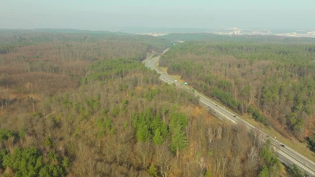 Busy freeway with cars driving both directions around bend between forest canopy in Poland