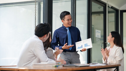 Asian businessman presenting data analysis to colleagues in a casual meeting. Team engagement and...